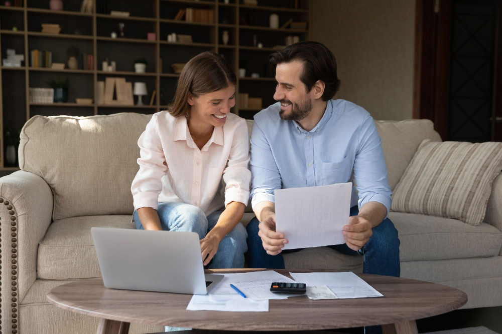 Young couple smiling at home while reviewing bankruptcy documents and planning finances with Brock Legal, LLC guidance.