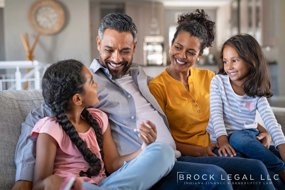 Smiling family on the couch, symbolizing the role of exemptions in Chapter 7 bankruptcy to protect assets in Indiana.