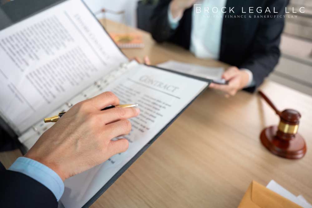A lawyer from Brock Legal and client review contract documents with a gavel in the background, signifying legal advice.