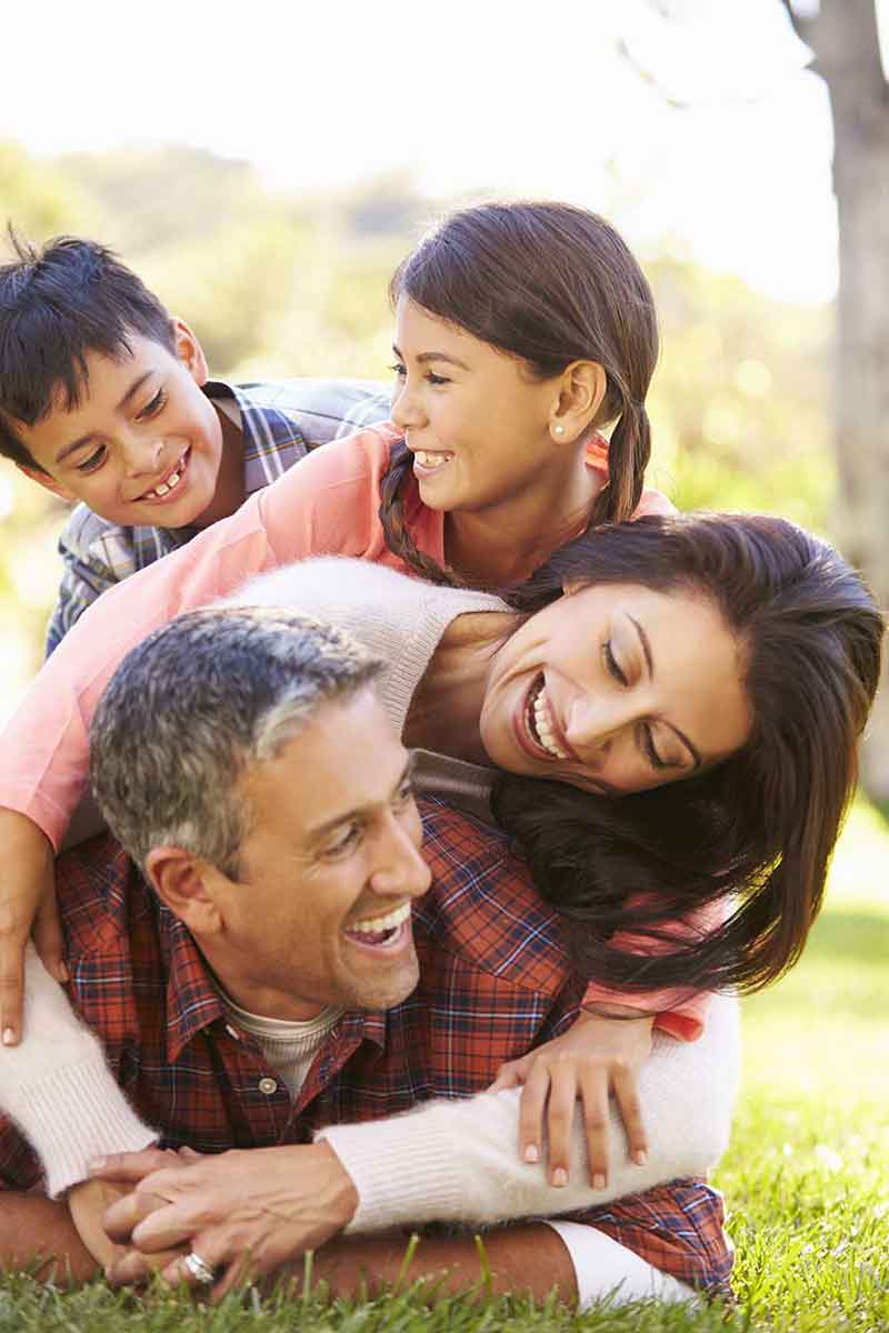 A joyful family of four is playfully stacked in a park, symbolizing happiness and stability. This image represents financial recovery and the trusted support of an Indiana bankruptcy attorney in achieving a secure future.| Brock Legal, LLC