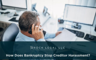 A professional man in a blue shirt talks on the phone while reviewing documents at a desk, emphasizing the trusted services of an Indiana bankruptcy lawyer for financial recovery and legal consultation.| Brock Legal, LLC