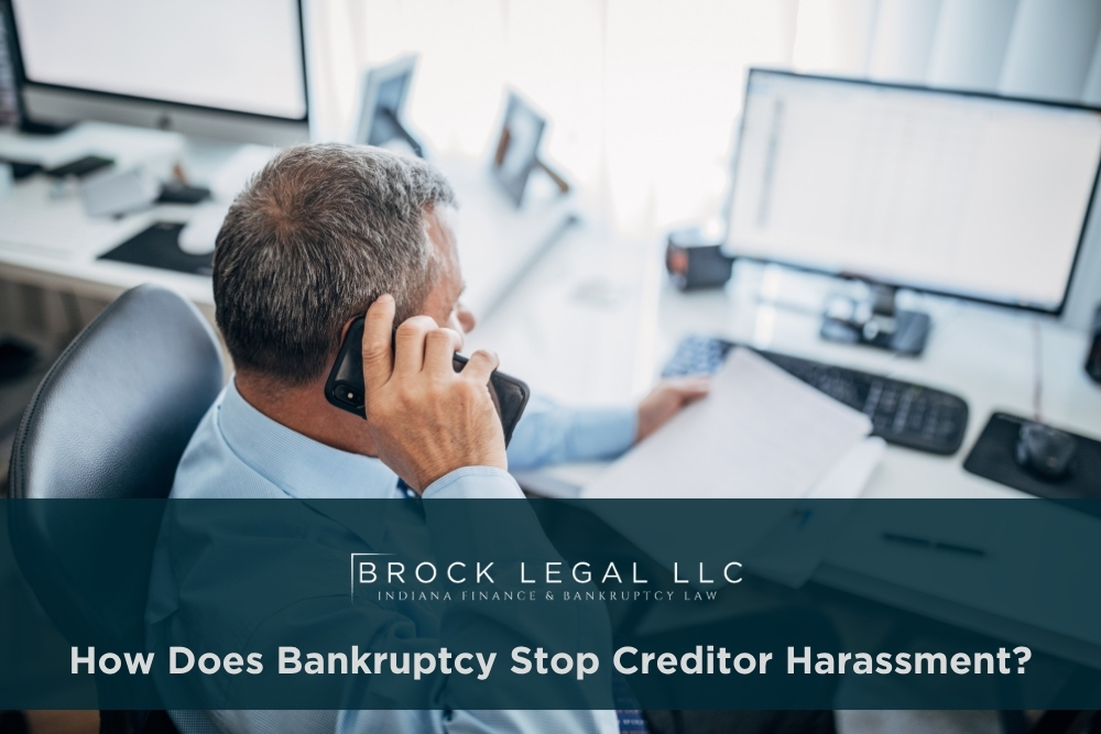 A professional man in a blue shirt talks on the phone while reviewing documents at a desk, emphasizing the trusted services of an Indiana bankruptcy lawyer for financial recovery and legal consultation.| Brock Legal, LLC